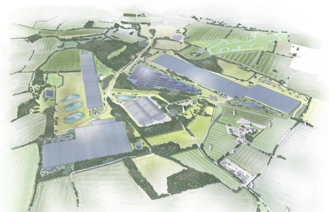 Aerial view of a solar power plant with multiple long solar panel arrays across green fields and roads linking the site.